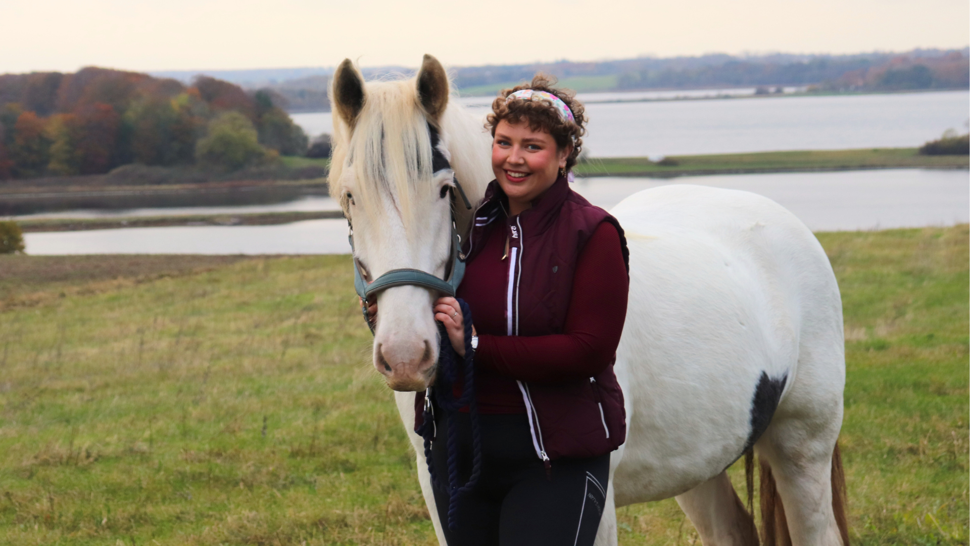 Hestemassør Line Holm-Bode fra EASE Equine Bodywork sammen med hesten Raffe ved vandet.